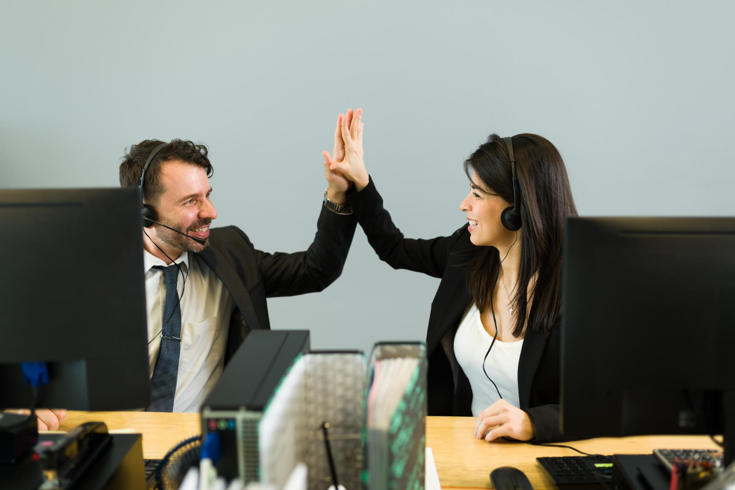 hispanic-man-young-woman-with-headset-doing-high-five-while-working-together-call-center-sales-representative-celebrating-business-sale