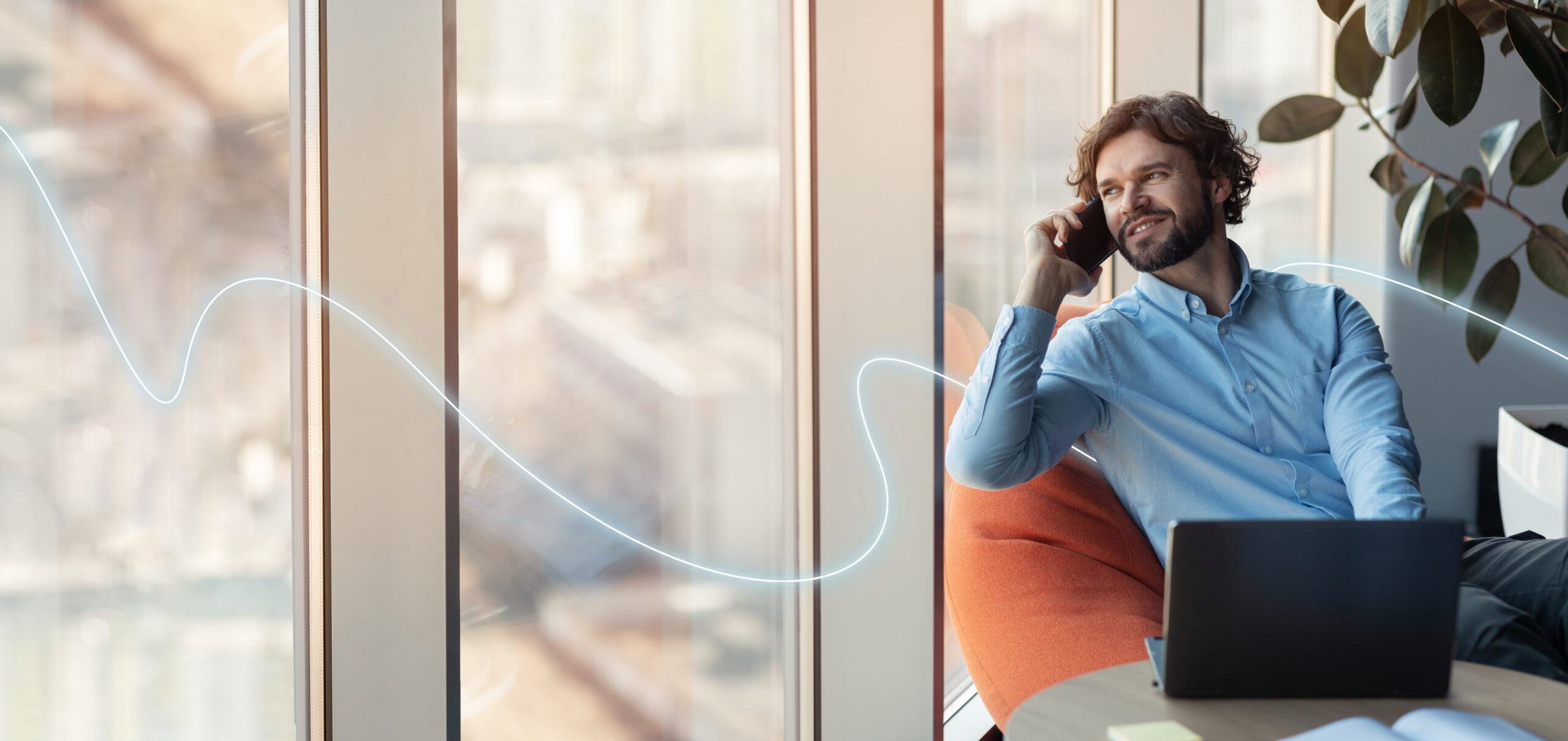 Smiling confident european millennial businessman with laptop calls by phone, looks out the window Smiling confident european millennial businessman with laptop calls by phone, looks out the window in office interior with abstract line, empty space. Work, professional and business communication